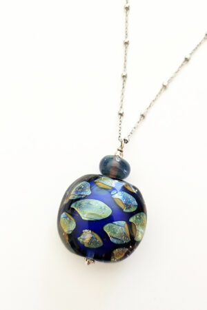 Gros plan du pendentif bleu "éclats de nuit" en verre de Murano avec éclats iridescents